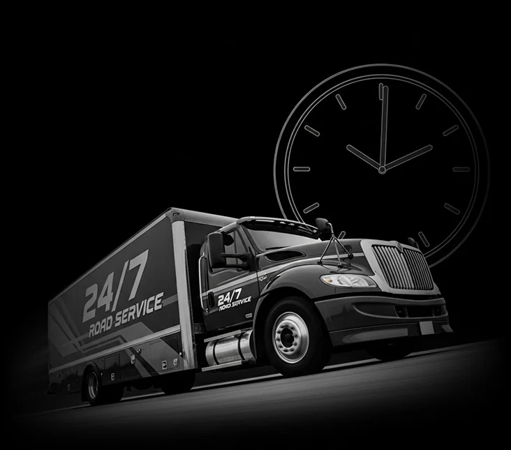 A 24/7 Road Service truck in front of a large clock